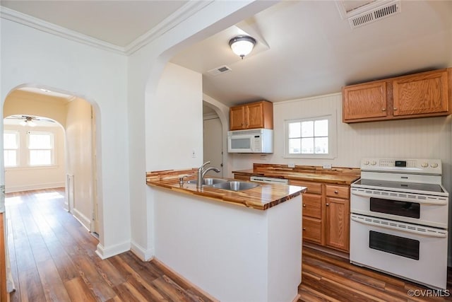 kitchen with a peninsula, white appliances, visible vents, and a sink