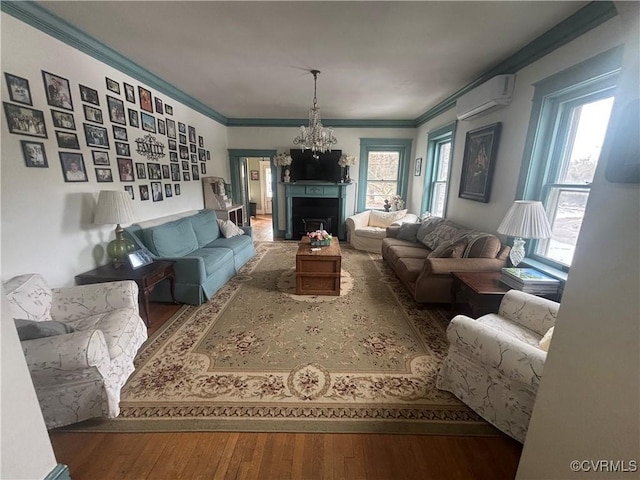 living room with ornamental molding, an AC wall unit, hardwood / wood-style floors, and an inviting chandelier