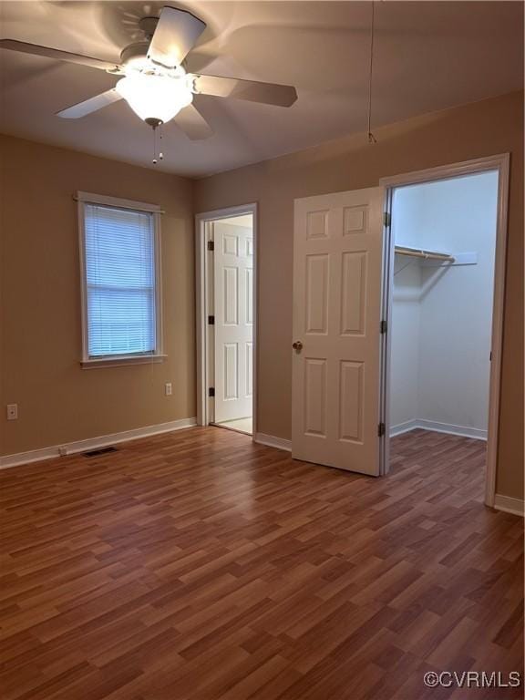 unfurnished bedroom with ceiling fan, dark hardwood / wood-style floors, a closet, and a spacious closet