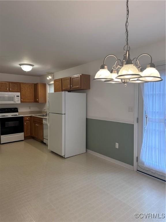 kitchen with sink, white appliances, hanging light fixtures, and a notable chandelier