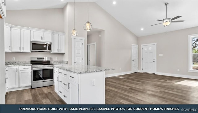 kitchen with stainless steel appliances, light stone counters, white cabinetry, and a center island