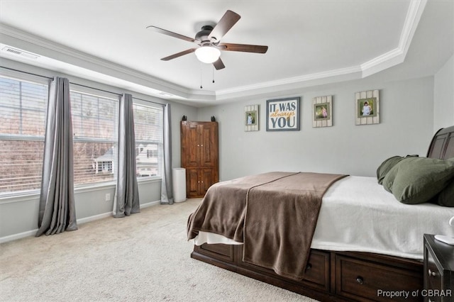 bedroom with a tray ceiling, crown molding, light colored carpet, visible vents, and baseboards