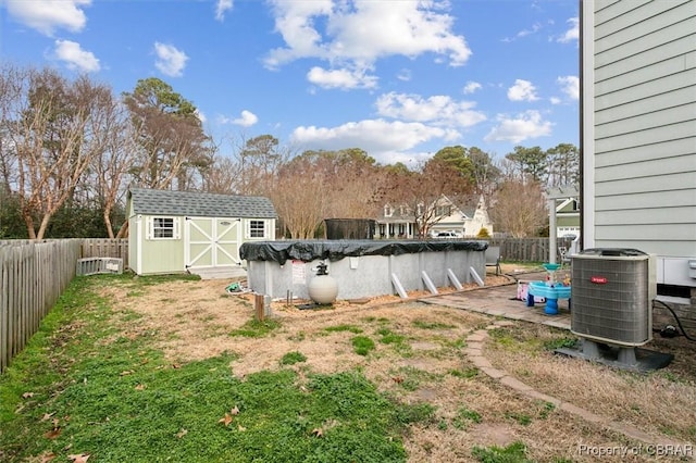 view of yard with a fenced backyard, central air condition unit, an outdoor structure, a fenced in pool, and a storage unit