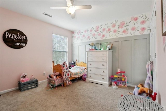 playroom with carpet floors, a wainscoted wall, visible vents, a decorative wall, and a ceiling fan