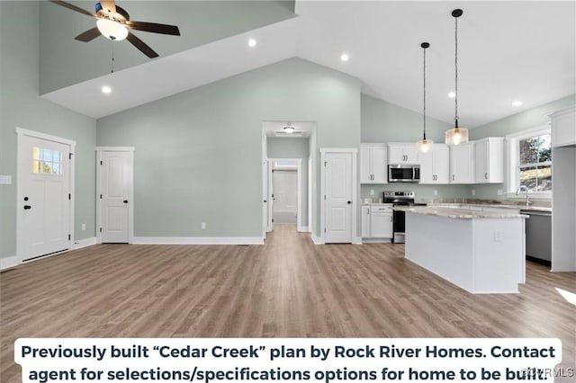 kitchen with hanging light fixtures, appliances with stainless steel finishes, white cabinets, and a center island