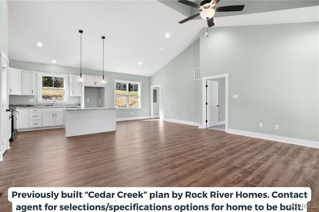 unfurnished living room featuring dark wood-style floors, baseboards, high vaulted ceiling, and a sink