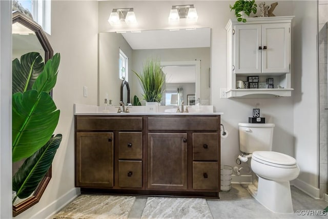full bath with baseboards, double vanity, and toilet