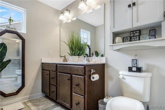 bathroom with double vanity, toilet, and baseboards