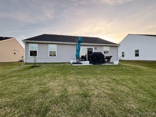 back of property at dusk featuring a yard and a patio area