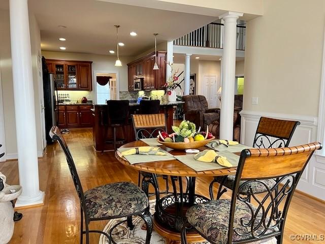 dining space with decorative columns and light hardwood / wood-style floors