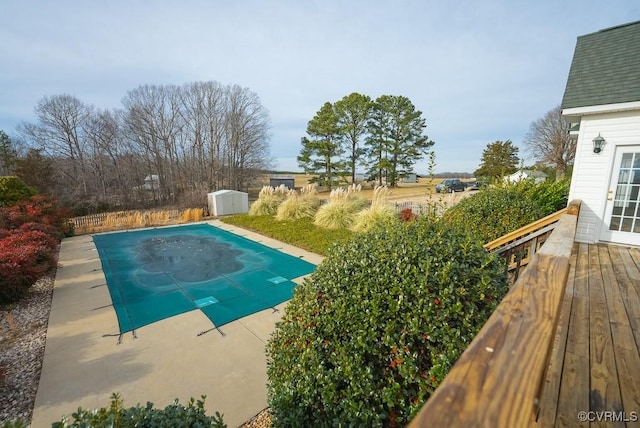 view of pool featuring a storage shed and a deck