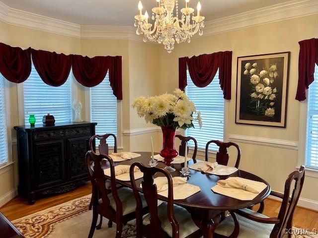 dining area featuring hardwood / wood-style floors, crown molding, and a notable chandelier