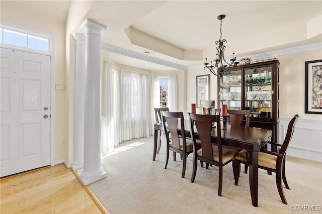 dining room with a tray ceiling, ornate columns, a notable chandelier, and a healthy amount of sunlight