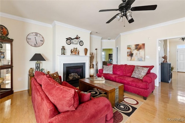 living room with ornamental molding, light hardwood / wood-style flooring, and ceiling fan