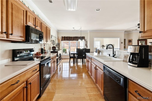 kitchen with sink, black appliances, crown molding, and pendant lighting