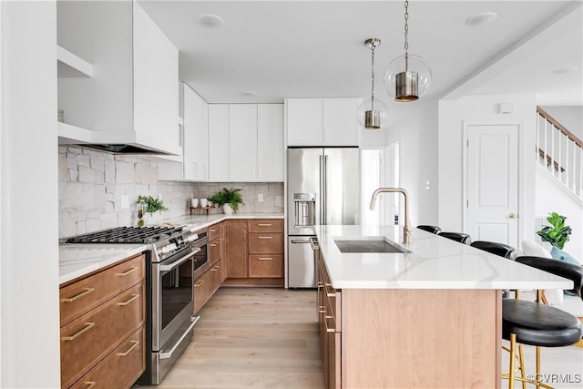 kitchen featuring a sink, appliances with stainless steel finishes, light wood finished floors, a kitchen bar, and tasteful backsplash