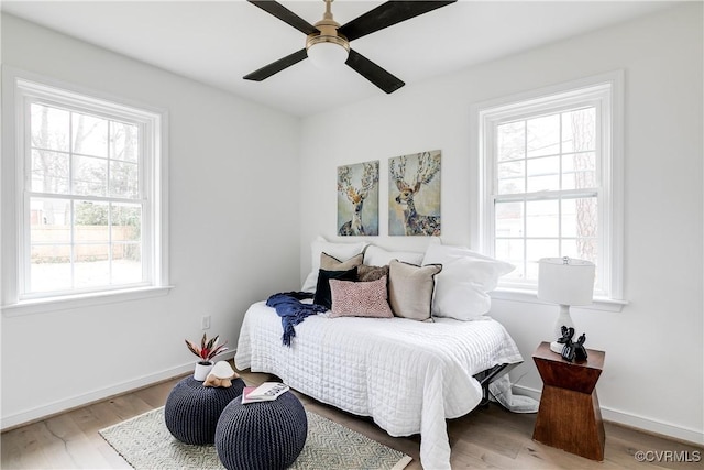 bedroom featuring multiple windows, baseboards, and wood finished floors