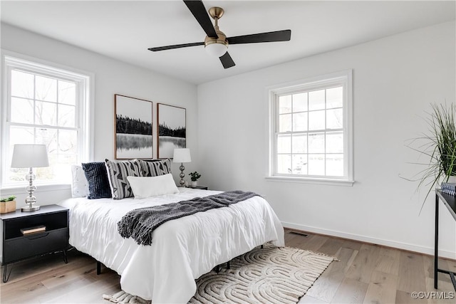 bedroom with baseboards, multiple windows, visible vents, and light wood-style floors