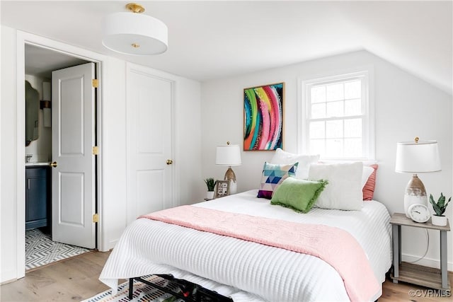 bedroom featuring light wood-style flooring and vaulted ceiling