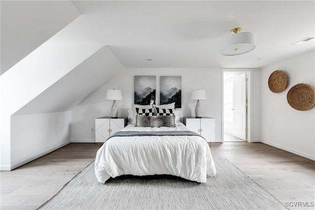 bedroom with baseboards, visible vents, and wood finished floors