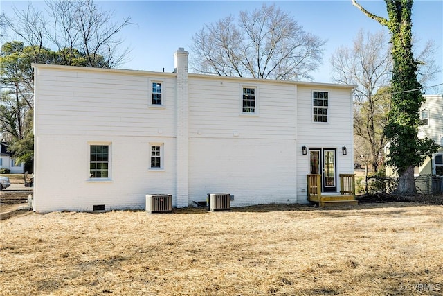 rear view of house featuring crawl space, brick siding, a chimney, and central air condition unit