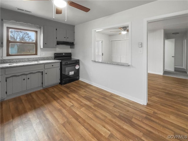 kitchen featuring gray cabinets, black range oven, sink, hardwood / wood-style flooring, and ceiling fan