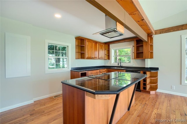 kitchen with sink, a center island, black appliances, light hardwood / wood-style floors, and a kitchen bar