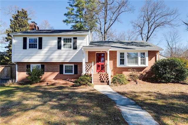 tri-level home with a front yard, a chimney, and brick siding