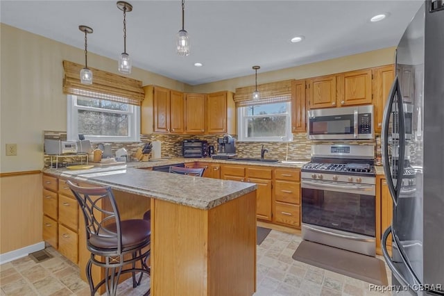 kitchen featuring appliances with stainless steel finishes, tasteful backsplash, sink, a kitchen bar, and kitchen peninsula