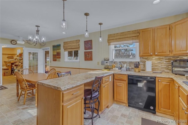 kitchen with pendant lighting, a breakfast bar, black dishwasher, light stone countertops, and kitchen peninsula