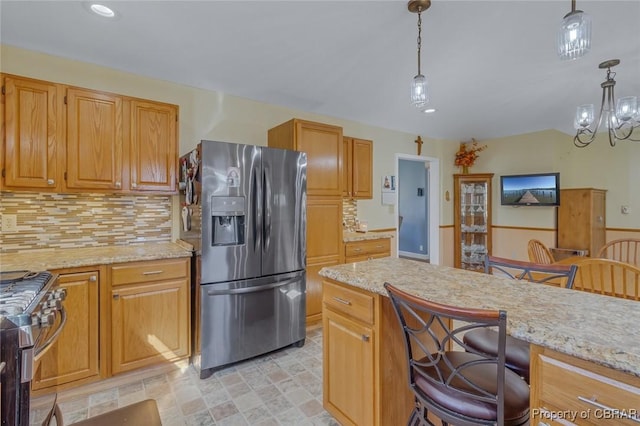 kitchen with light stone countertops, decorative light fixtures, stainless steel appliances, and a kitchen bar