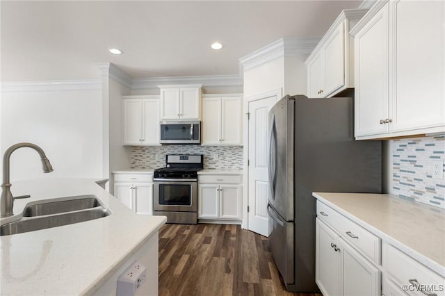 kitchen with appliances with stainless steel finishes, white cabinets, dark hardwood / wood-style flooring, ornamental molding, and sink