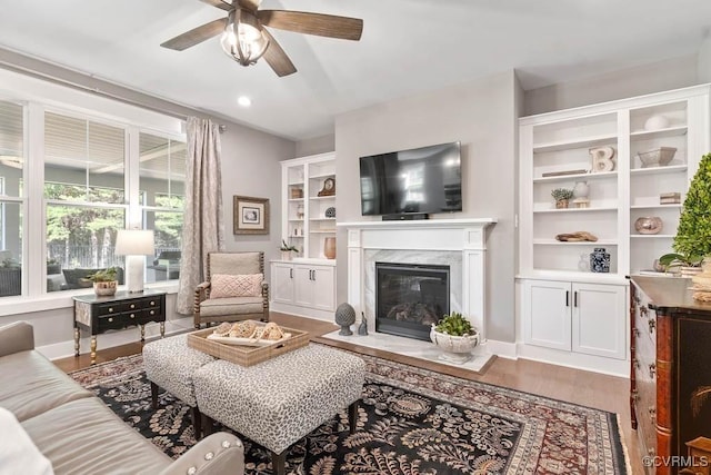 living room featuring ceiling fan, recessed lighting, a premium fireplace, wood finished floors, and baseboards