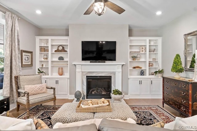 living room featuring recessed lighting, light wood-style flooring, a ceiling fan, and a high end fireplace