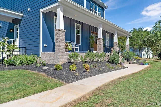 entrance to property with covered porch, board and batten siding, and a yard