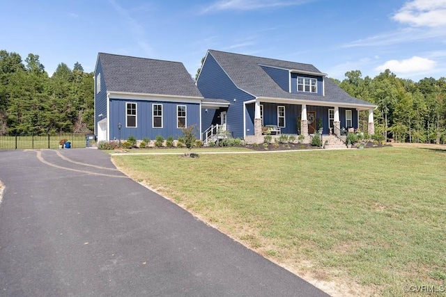 view of front of property featuring covered porch, fence, board and batten siding, and a front yard