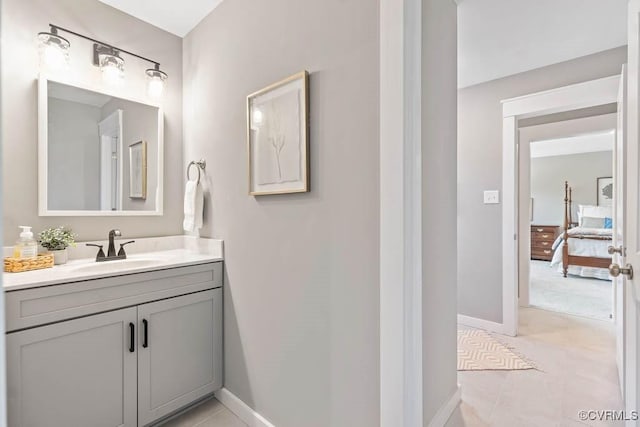 bathroom with connected bathroom, vanity, baseboards, and tile patterned floors