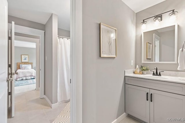 bathroom with curtained shower, vanity, baseboards, tile patterned floors, and ensuite bath