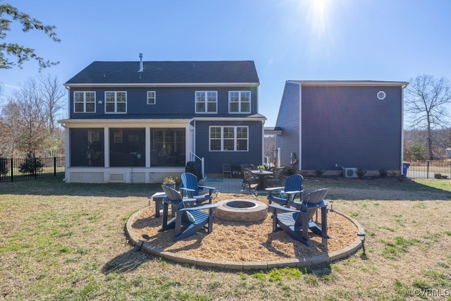 back of house featuring a sunroom, an outdoor fire pit, fence, and a yard