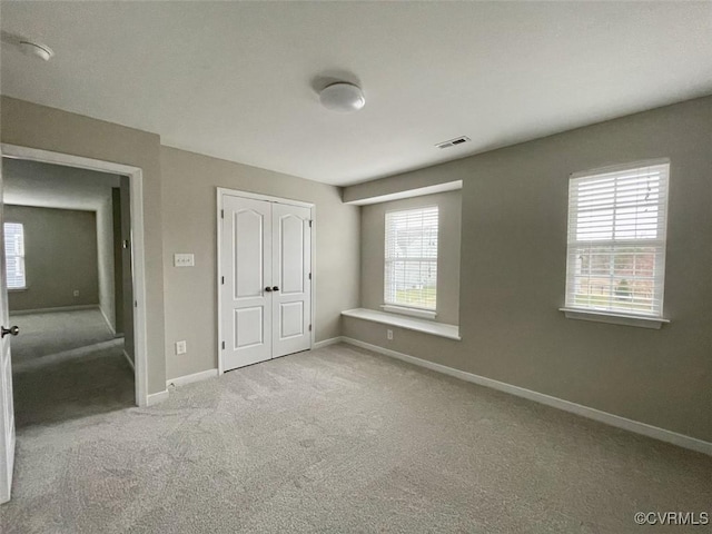 unfurnished bedroom with baseboards, a closet, visible vents, and carpet flooring