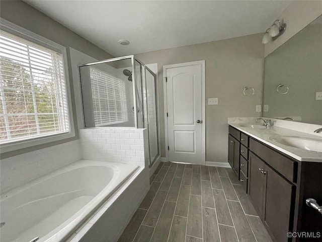 full bathroom featuring a bath, a shower stall, a sink, and wood finish floors