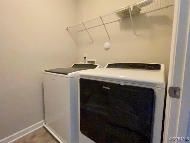 washroom featuring washing machine and dryer, laundry area, and baseboards