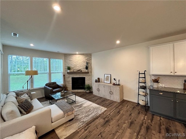 living area with a fireplace, visible vents, dark wood finished floors, and recessed lighting