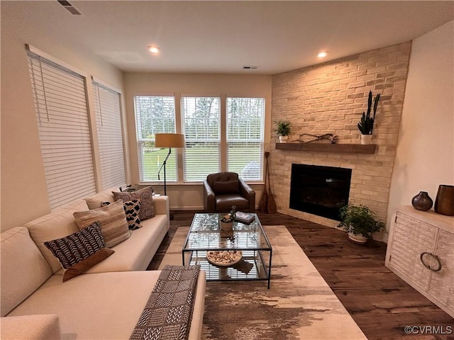 living area with a brick fireplace, wood finished floors, visible vents, and recessed lighting