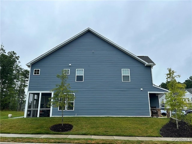 view of side of home with a sunroom and a lawn