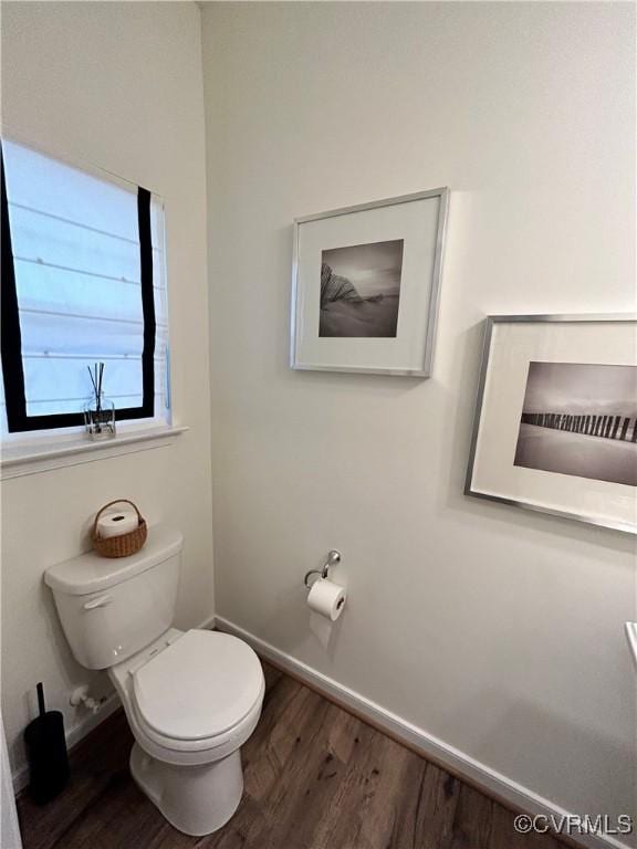 bathroom with toilet, baseboards, and wood finished floors