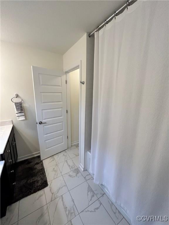 full bath with marble finish floor, baseboards, curtained shower, and vanity