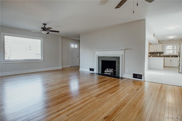 unfurnished living room featuring sink, ceiling fan, and light hardwood / wood-style flooring