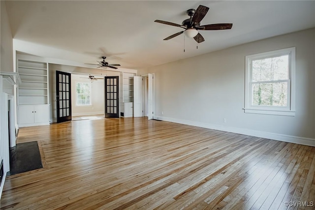 unfurnished living room with light hardwood / wood-style flooring, ceiling fan, french doors, and built in features