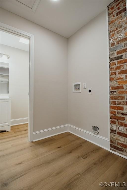 clothes washing area with brick wall, light hardwood / wood-style floors, washer hookup, and electric dryer hookup